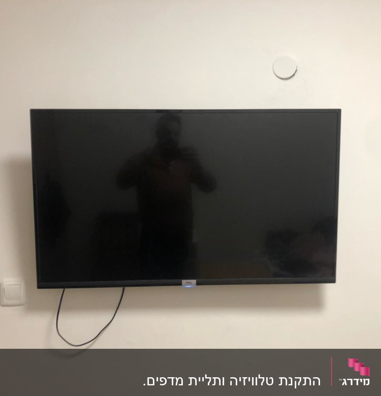 טלוויזיה תלויה על הקיר עם כבל חשמל